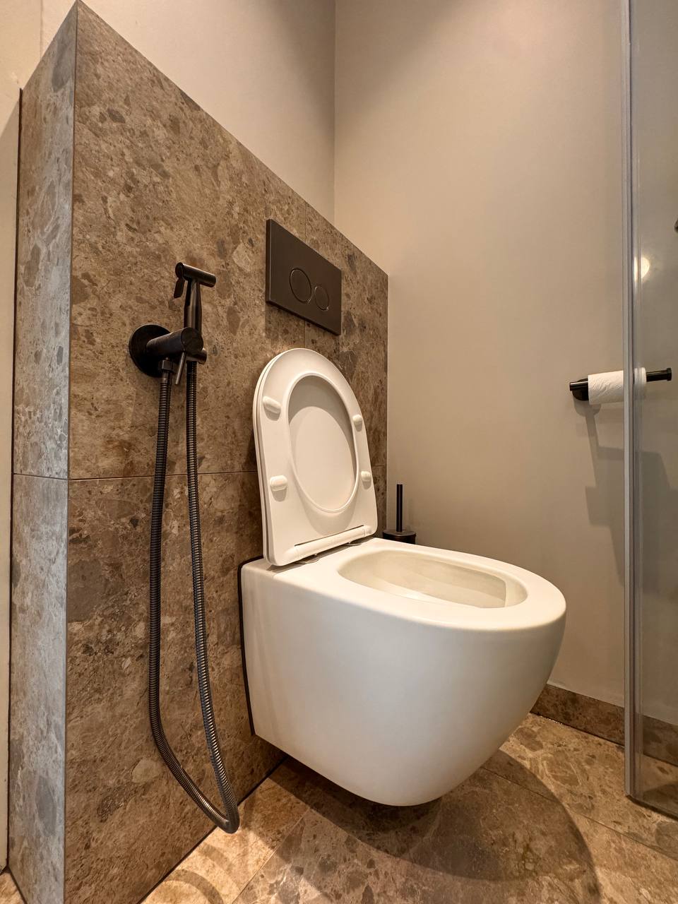 Wandhangend toilet met steenlook tegels en zwarte accessoires